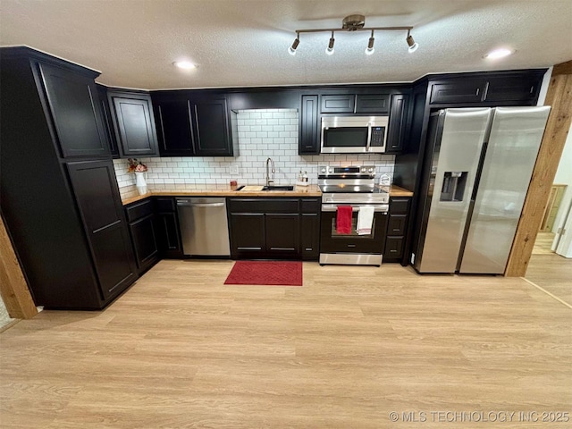 kitchen with stainless steel appliances, sink, backsplash, and light hardwood / wood-style floors