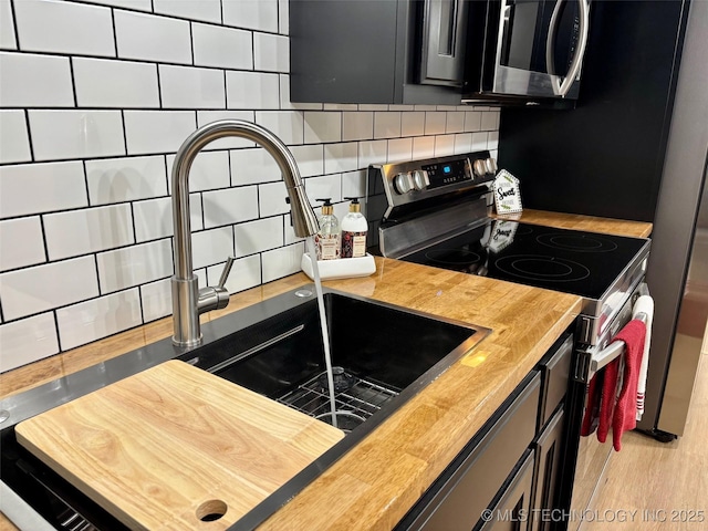 kitchen featuring backsplash, light hardwood / wood-style flooring, stainless steel appliances, and wooden counters