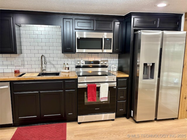 kitchen featuring tasteful backsplash, sink, light hardwood / wood-style floors, and appliances with stainless steel finishes