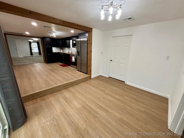 interior space featuring beamed ceiling, sink, a textured ceiling, and light hardwood / wood-style flooring