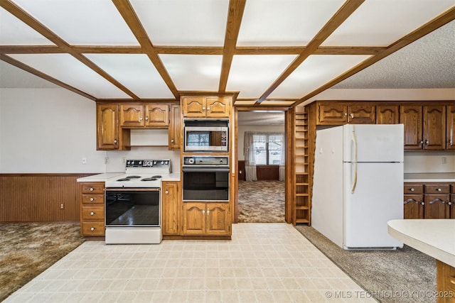 kitchen with white appliances, light carpet, and wood walls