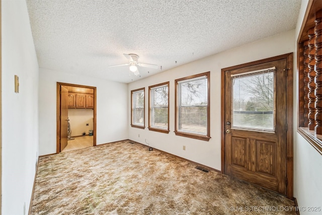 entryway with ceiling fan, light carpet, and a textured ceiling