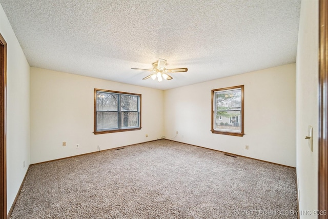 carpeted spare room featuring a textured ceiling and ceiling fan