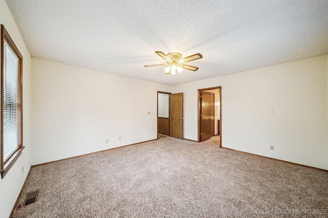 unfurnished bedroom featuring ceiling fan, light colored carpet, ensuite bath, and a textured ceiling