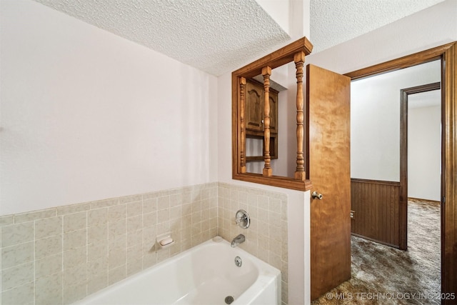 bathroom with a bathtub, wooden walls, and a textured ceiling