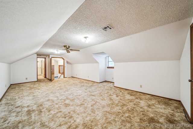 bonus room featuring vaulted ceiling, carpet, ceiling fan, and a textured ceiling