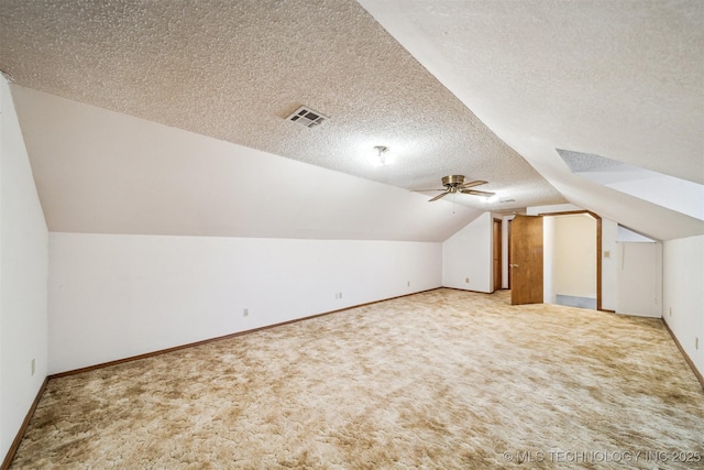 additional living space with ceiling fan, lofted ceiling, light carpet, and a textured ceiling