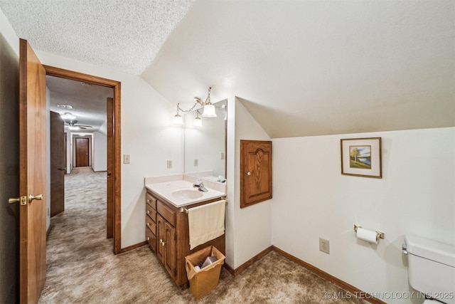 bathroom with lofted ceiling, vanity, toilet, and a textured ceiling