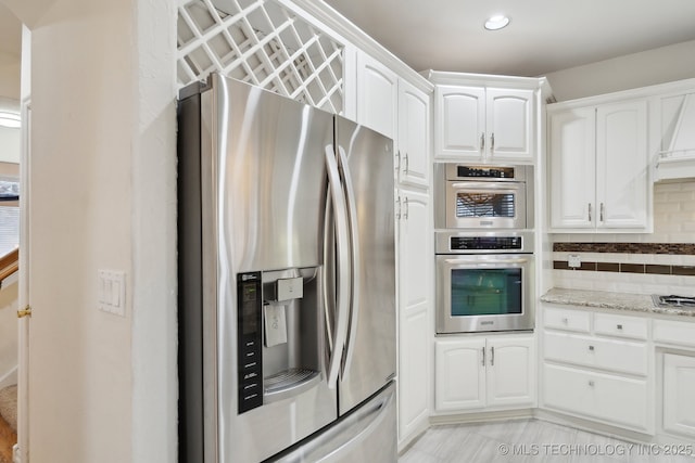 kitchen with stainless steel refrigerator with ice dispenser, light stone countertops, white cabinets, and decorative backsplash