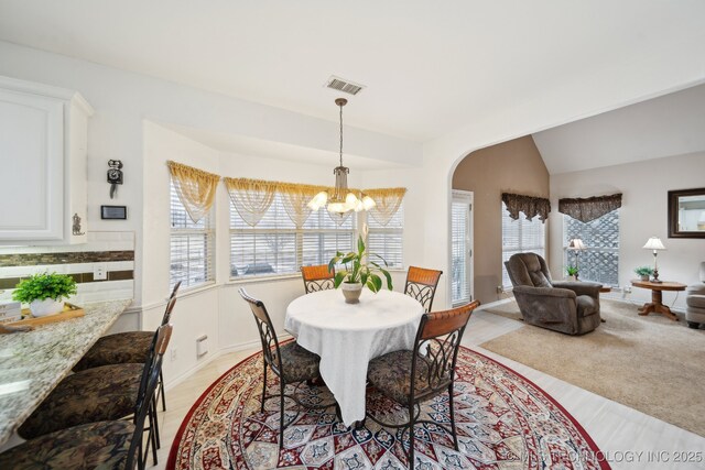 dining room with vaulted ceiling and an inviting chandelier