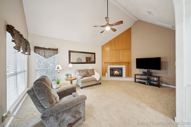 living room with a tile fireplace, carpet flooring, ceiling fan, and high vaulted ceiling