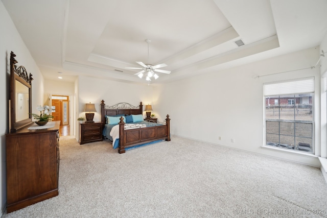 carpeted bedroom with ceiling fan and a tray ceiling