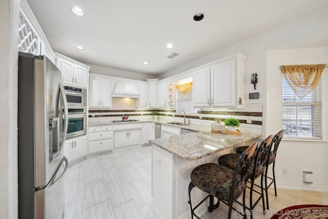 8402 N 100th E Ave, Owasso, OK 74055 - kitchen featuring stainless steel appliances, a peninsula, backsplash, white cabinets, and recessed lighting
