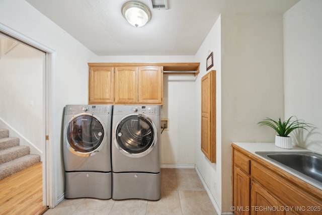 washroom with sink, light tile patterned floors, cabinets, and washing machine and clothes dryer