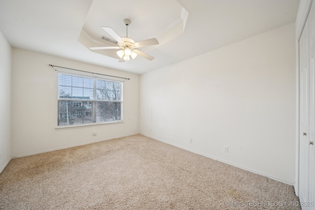 carpeted spare room featuring ceiling fan and a tray ceiling