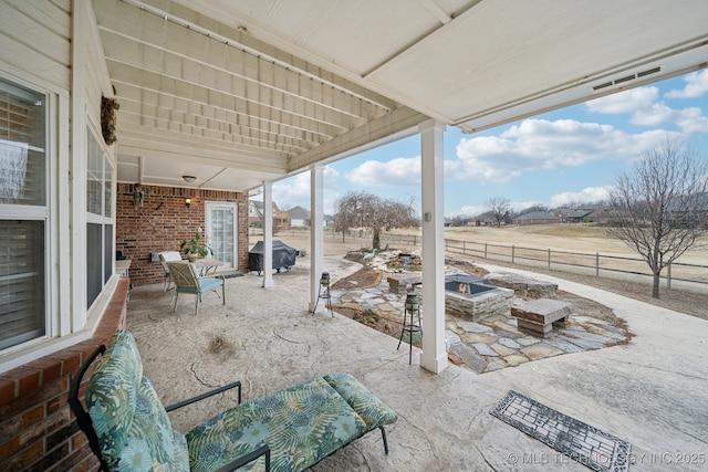 view of patio with grilling area, an outdoor fire pit, and a rural view