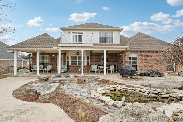 back of property featuring a fire pit, a patio area, and a balcony