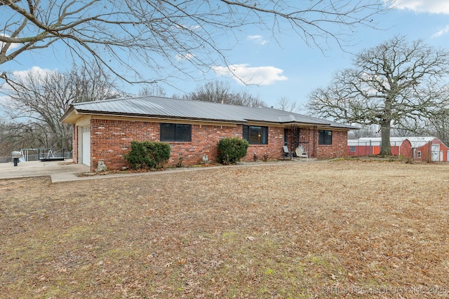 single story home featuring a garage, brick siding, and metal roof