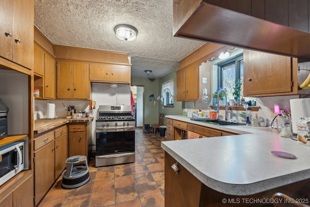 kitchen featuring sink, kitchen peninsula, a textured ceiling, and appliances with stainless steel finishes