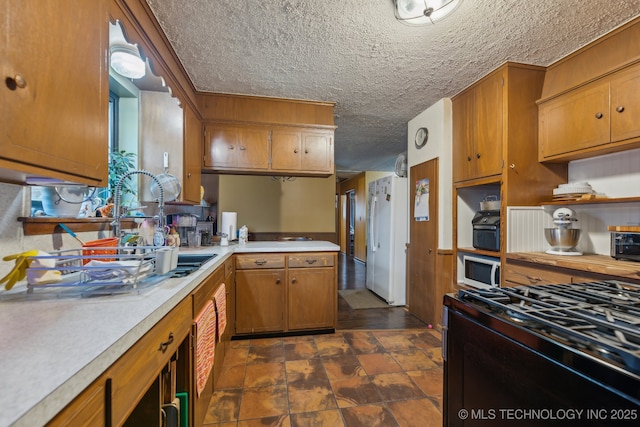 kitchen featuring white refrigerator, range with gas cooktop, and a textured ceiling