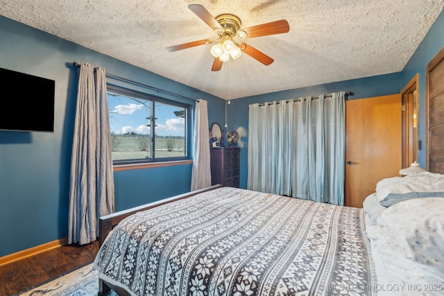 bedroom with a textured ceiling, ceiling fan, wood finished floors, and baseboards