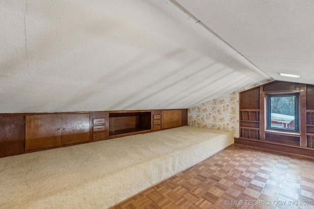 additional living space featuring light parquet flooring, lofted ceiling, and a textured ceiling