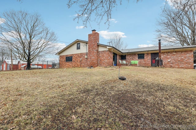 back of property with a yard, brick siding, and a chimney