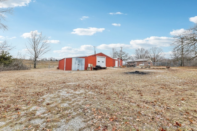 view of yard with a garage, an outdoor structure, and a rural view