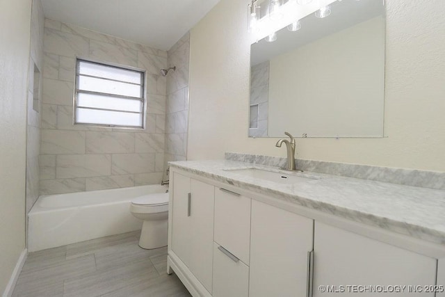 full bathroom with tiled shower / bath, vanity, and toilet