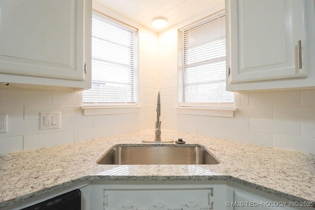 kitchen featuring white cabinetry, light stone countertops, sink, and backsplash