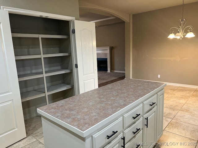 kitchen with pendant lighting, light tile patterned floors, white cabinetry, a center island, and a fireplace