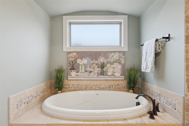 bathroom featuring tiled tub and vaulted ceiling