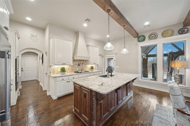 kitchen with sink, white cabinetry, custom range hood, stainless steel appliances, and light stone countertops