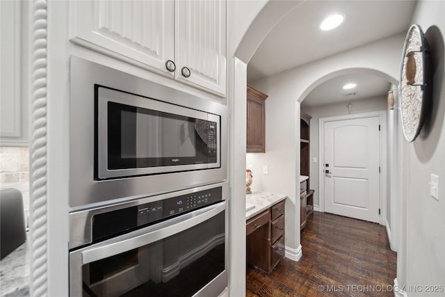 kitchen with stainless steel appliances, dark hardwood / wood-style floors, white cabinets, and light stone counters