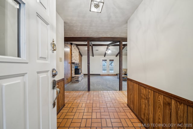 corridor with vaulted ceiling with beams, french doors, and wood walls