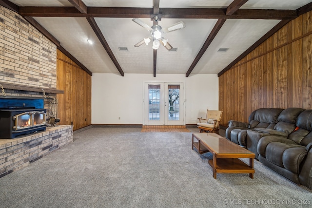 carpeted living room with french doors, vaulted ceiling with beams, and wood walls