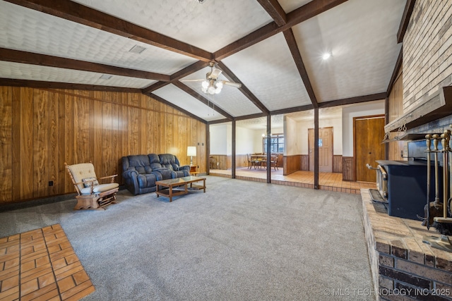 carpeted living room featuring wooden walls, lofted ceiling with beams, and ceiling fan