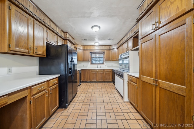 kitchen featuring black fridge with ice dispenser, sink, and oven