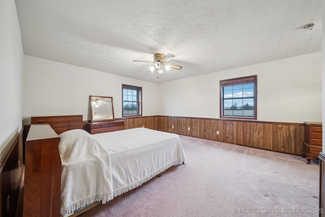 carpeted bedroom featuring ceiling fan, a textured ceiling, and wooden walls