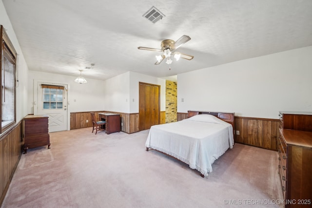 carpeted bedroom featuring ceiling fan, wooden walls, and a textured ceiling