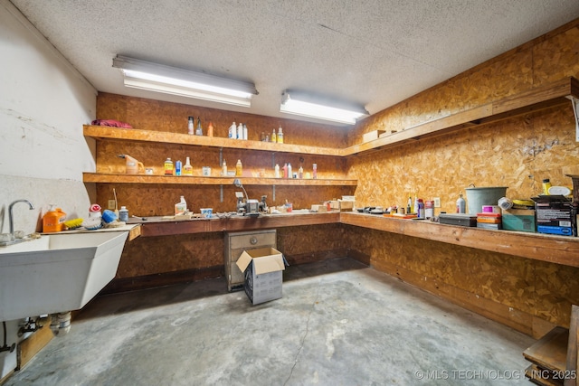 miscellaneous room featuring sink, a textured ceiling, a workshop area, and concrete floors