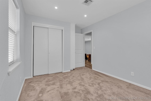 unfurnished bedroom with light colored carpet and a closet