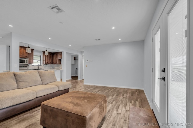 living room featuring sink and light hardwood / wood-style flooring