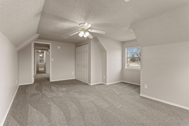 additional living space featuring carpet, a textured ceiling, lofted ceiling, and ceiling fan