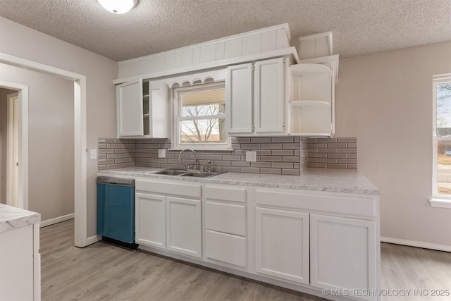 kitchen featuring dishwashing machine, sink, light hardwood / wood-style flooring, and white cabinets