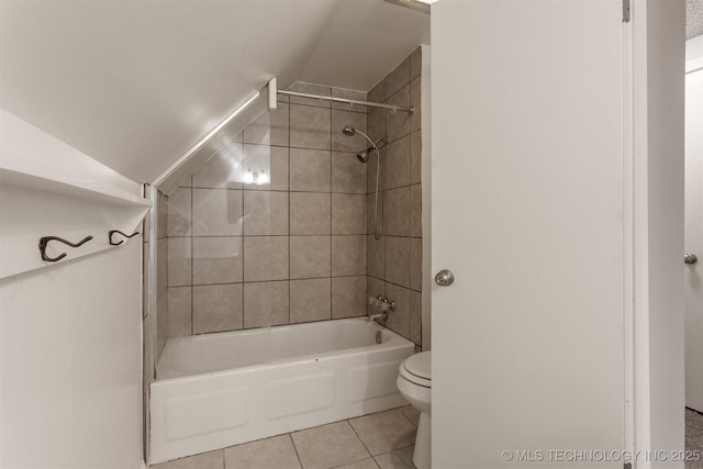 bathroom featuring tile patterned flooring, tiled shower / bath combo, lofted ceiling, and toilet