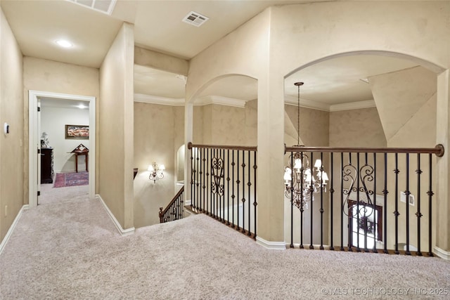 hallway featuring crown molding, a chandelier, and carpet floors