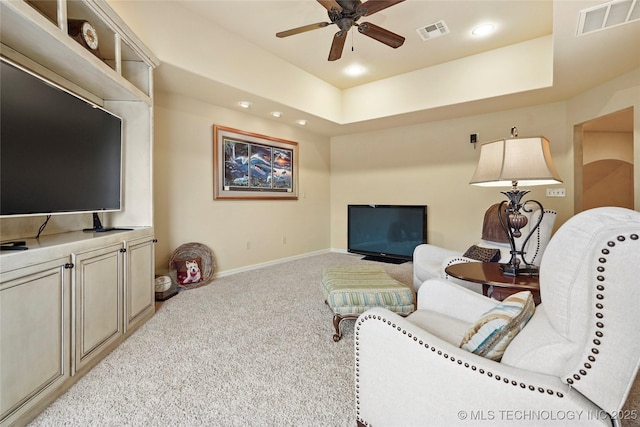 carpeted living room featuring a tray ceiling and ceiling fan