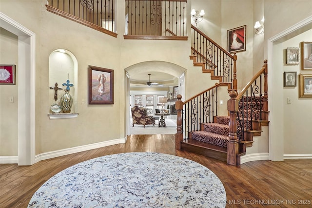 entryway with a high ceiling, hardwood / wood-style floors, and ceiling fan