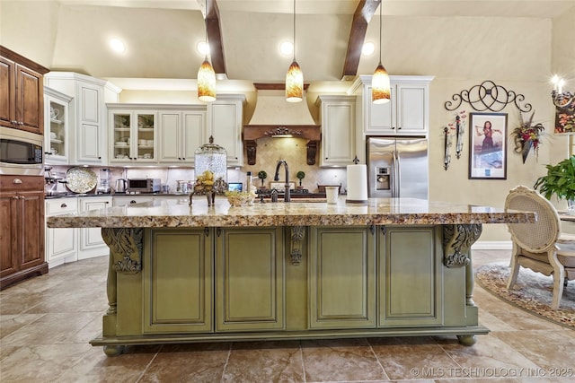 kitchen featuring pendant lighting, premium range hood, a kitchen island with sink, dark stone countertops, and stainless steel appliances